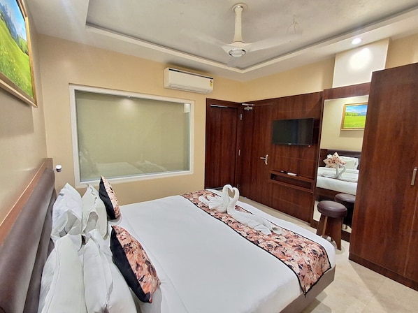 A hotel room with a bed, a window, a TV, a wardrobe, and a bathroom.