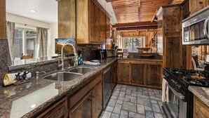 Una cocina con encimeras de granito, armarios de madera, un lavamanos de acero inoxidable y un horno empotrado.