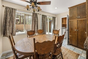 A dining room with a wooden table and chairs, a chandelier, and a large wooden cabinet. - Walk to Snow Summit, Hot Tub, AC, Tesla Charger & Fire Pit, Evergreen Cabin (Big Bear Lake)