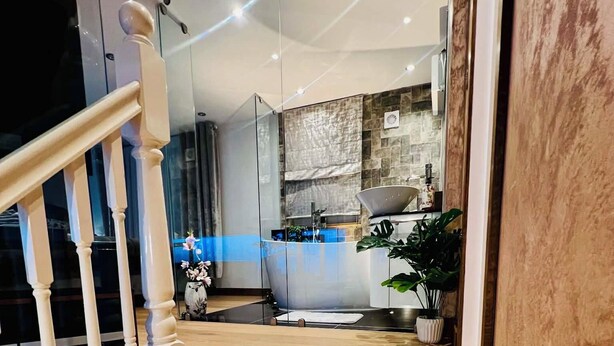 Una escalera que lleva a un baño con bañera, lavabo y espejo.