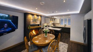 Una cocina moderna con comedor, chimenea y televisor de pantalla plana en la pared.