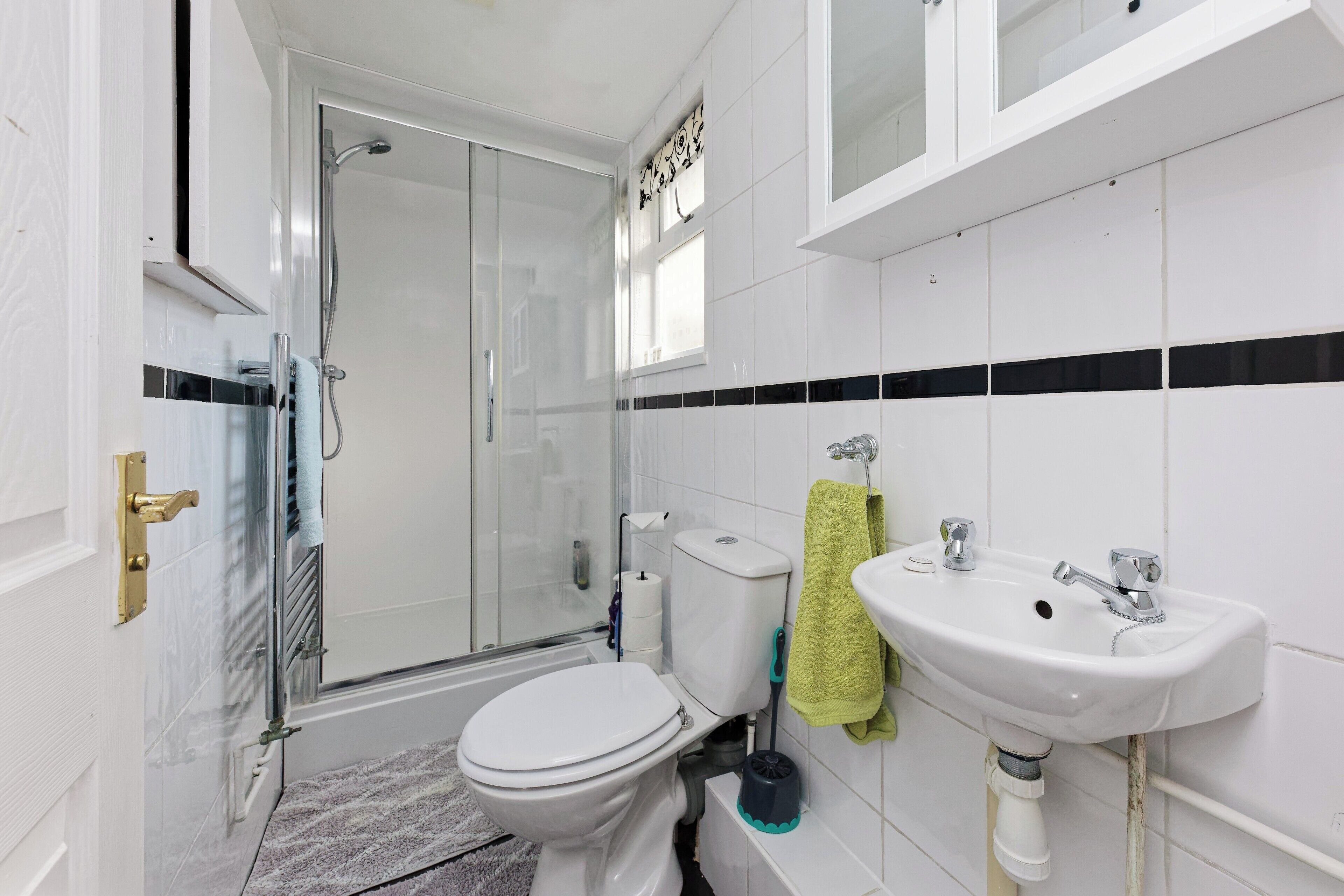 A bathroom with a toilet, sink, shower, and glass-enclosed shower stall.