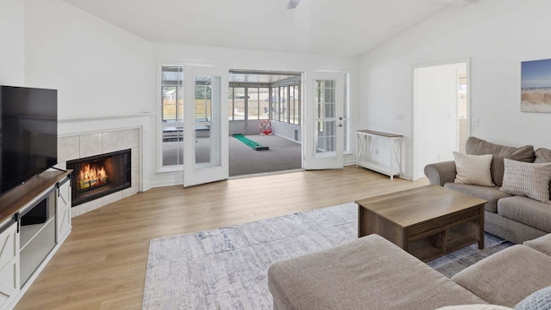 Ein geräumiges Wohnzimmer mit Kamin, Fernseher, Deckenventilator und großem Fenster.