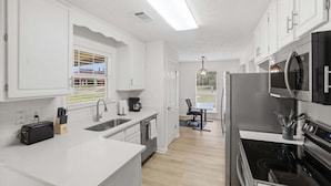 Eine moderne Küche mit weißen Schränken, einem eingebauten Backofen, einer Mikrowelle und einem Essbereich mit Tisch und Stühlen.