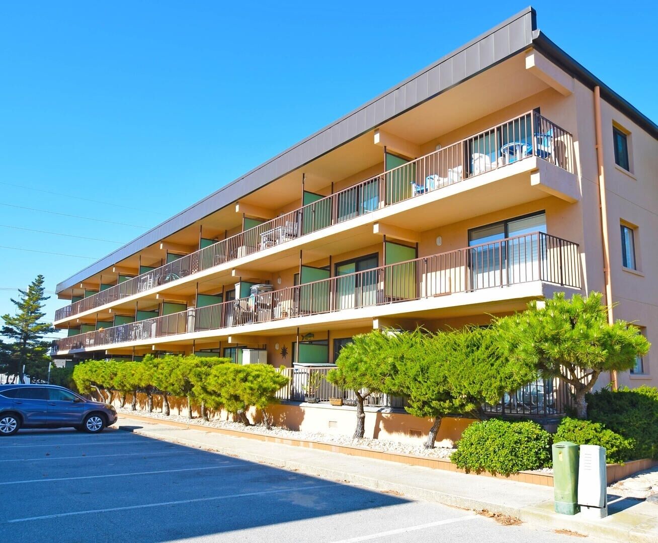 A multi-story residential building with balconies, a parking lot, and well-maintained landscaping.