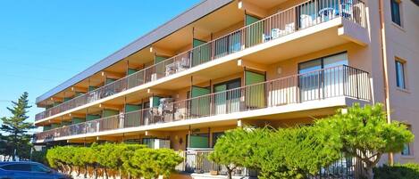 A multi-story residential building with balconies, a parking lot, and well-maintained landscaping.