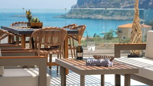 Eine Terrasse mit Korbmöbeln, einer Weinflasche und zwei Gläsern.