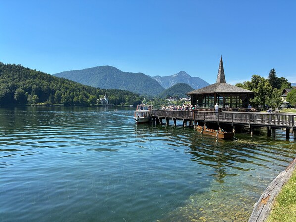 A wooden pier extending into a lake with a gazebo and a boat docked at the end.