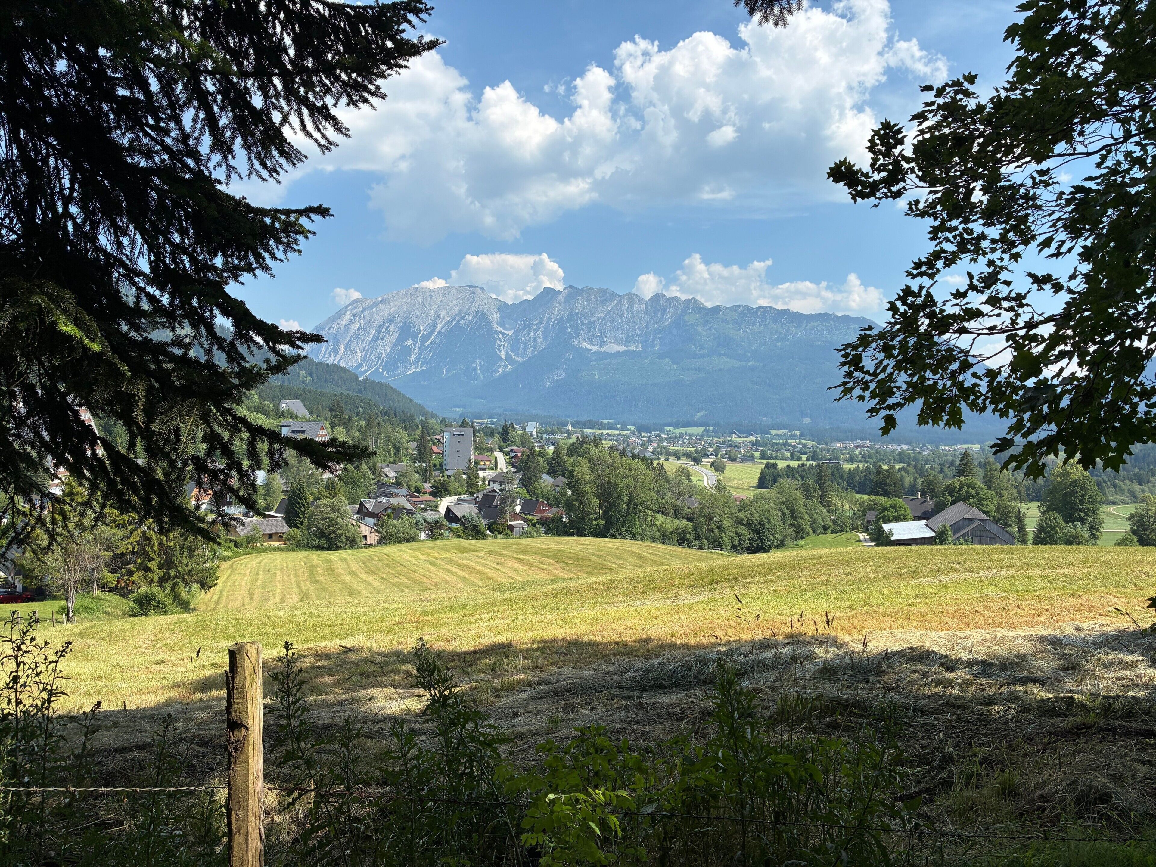 A rural landscape with a mountain range in the background, a small village, and a field in the foreground.