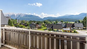 A residential area with houses, a wooden fence, and a mountain range in the background. - Grimmingblick Apartment with Pool and Spacious Terrace (Sonnenalm)