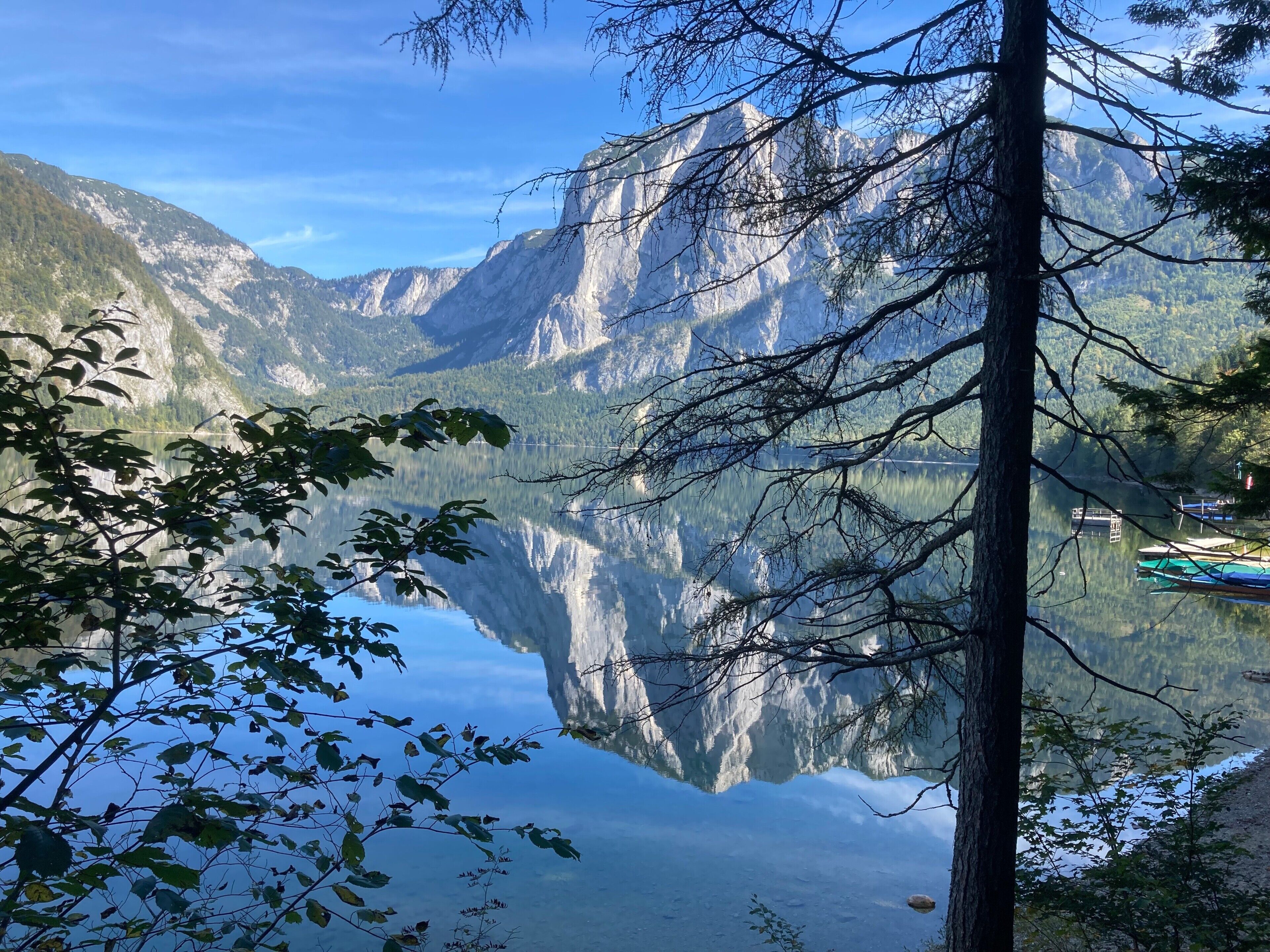 Ein Bergsee mit Spiegelungen, umgeben von Bäumen und Bergen.