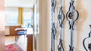 A hallway with a patterned metal railing, a wooden floor, and a red patterned rug. - Grimmingblick Apartment with Pool and Spacious Terrace (Sonnenalm)