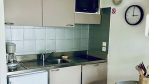Une cuisine compacte équipée d’un four à micro-ondes, d’un évier et d’un petit réfrigérateur.