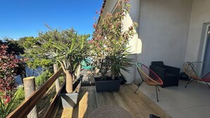 Un balcon agrémenté de plantes en pot, de meubles d’extérieur et d’une rambarde en bois.