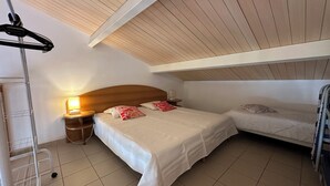 Une chambre à coucher comprenant un lit, deux tables de chevet, une commode, une lampe et un ventilateur de plafond.