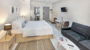 Moderni hotellihuone, jossa on sänky, sohva, työpöytä ja televisio.