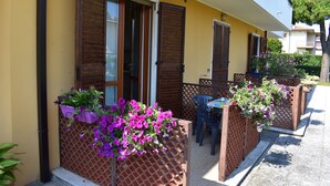 Ein gelbes Gebäude mit Holzhinterfenstern, Außenbestuhlung und Blumenkästen.