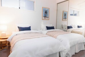 Habitación de hotel con dos camas, una mesita de noche con lámpara y un espejo grande.