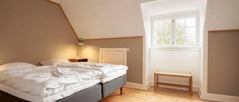 A bedroom with a bed, a bench, a nightstand, and a window.