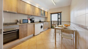 Una cucina moderna con mobili in legno, una lavatrice, un forno a microonde e un'area pranzo con tavolo e sedie.