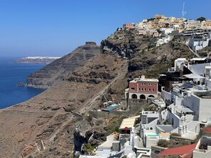 A coastal town with buildings on a hillside, a rocky cliff, and the sea. - Great location and beautiful view (Fira)