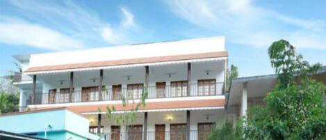 A two-story building with a flat roof, multiple balconies, and a central staircase.