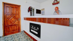 Un área de recepción con puerta de madera, mostrador, reloj de pared, calendario y un retrato enmarcado.