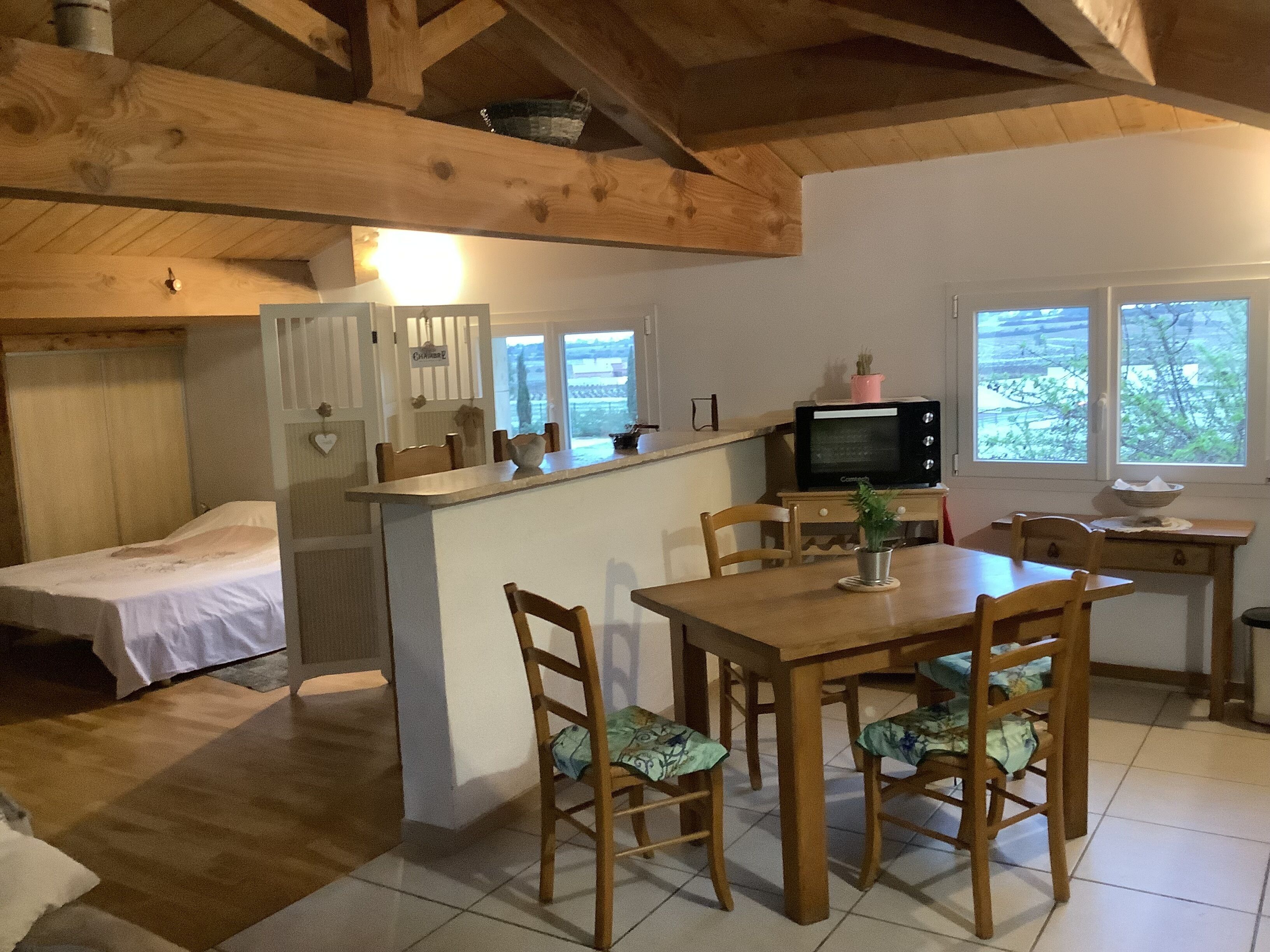 Une cuisine compacte équipée d’un four à micro-ondes, d’une petite table à manger avec des chaises, d’un réfrigérateur et d’une fenêtre donnant sur un beau paysage.