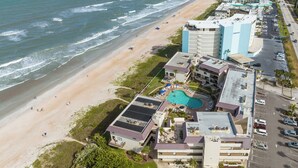 Ilmakuva rannikolla sijaitsevasta hotellista, jossa on ranta, uima-allas ja useita rakennuksia.