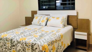 A bedroom with a bed, a nightstand, a window with blinds, and an air conditioning unit. - Serene 2-bedroom Apartment With Private Pool in Sabana de la Mar (Sabana de la Mar)