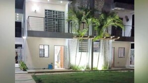 A two-story building with a balcony, a small garden area, and a visible door. - Serene 2-bedroom Apartment With Private Pool in Sabana de la Mar (Sabana de la Mar)