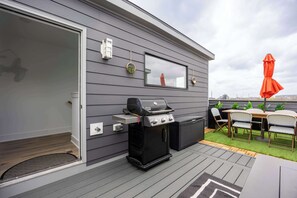 A modern outdoor patio with a grill, outdoor seating, and a view of the city skyline. - Luxury Townhouse with Skyline Views & Rooftop BBQ (Indianapolis)