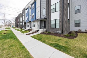 A row of modern townhouses with a central walkway, front steps, and a well-maintained lawn. - Luxury Townhouse with Skyline Views & Rooftop BBQ (Indianapolis)