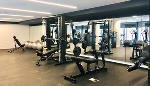 A gym with various exercise equipment, including weight machines and free weights, and a mirrored wall. - Luxury 2BR2BA Apt MQ+ Pool+Gym in Mel  Docklands (Docklands)