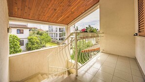 Ein Balkon mit Holzboden, Metallgeländer und Blick auf eine Wohngegend.