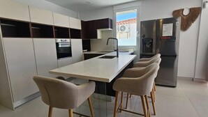 A modern kitchen with a central island, built-in oven, and refrigerator. - VILLA SEA VIEWS V7 (Amarilla Golf)