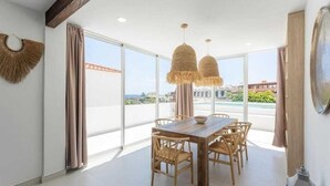 A dining area with a wooden table and chairs, large windows, and a view of the cityscape. - VILLA SEA VIEWS V7 (Amarilla Golf)