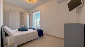 Ein Hotelzimmer mit Bett, Schreibtisch, Flachbildfernseher und einem Fenster mit Blick.