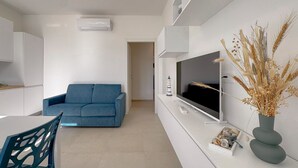 Ein modernes Wohnzimmer mit einer Couch, einem Fernseher und einer dekorativen Vase.