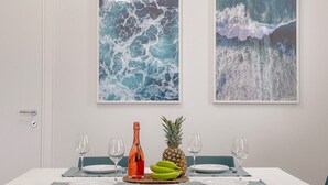 Ein Esstisch mit einer Flasche, einer Ananas und Bananen, zwei leeren Weingläsern und zwei leeren Tellern.