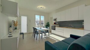 Eine moderne Küche mit weißen Schränken, einem Essbereich mit Tisch und Stühlen sowie einem eingebauten Backofen.