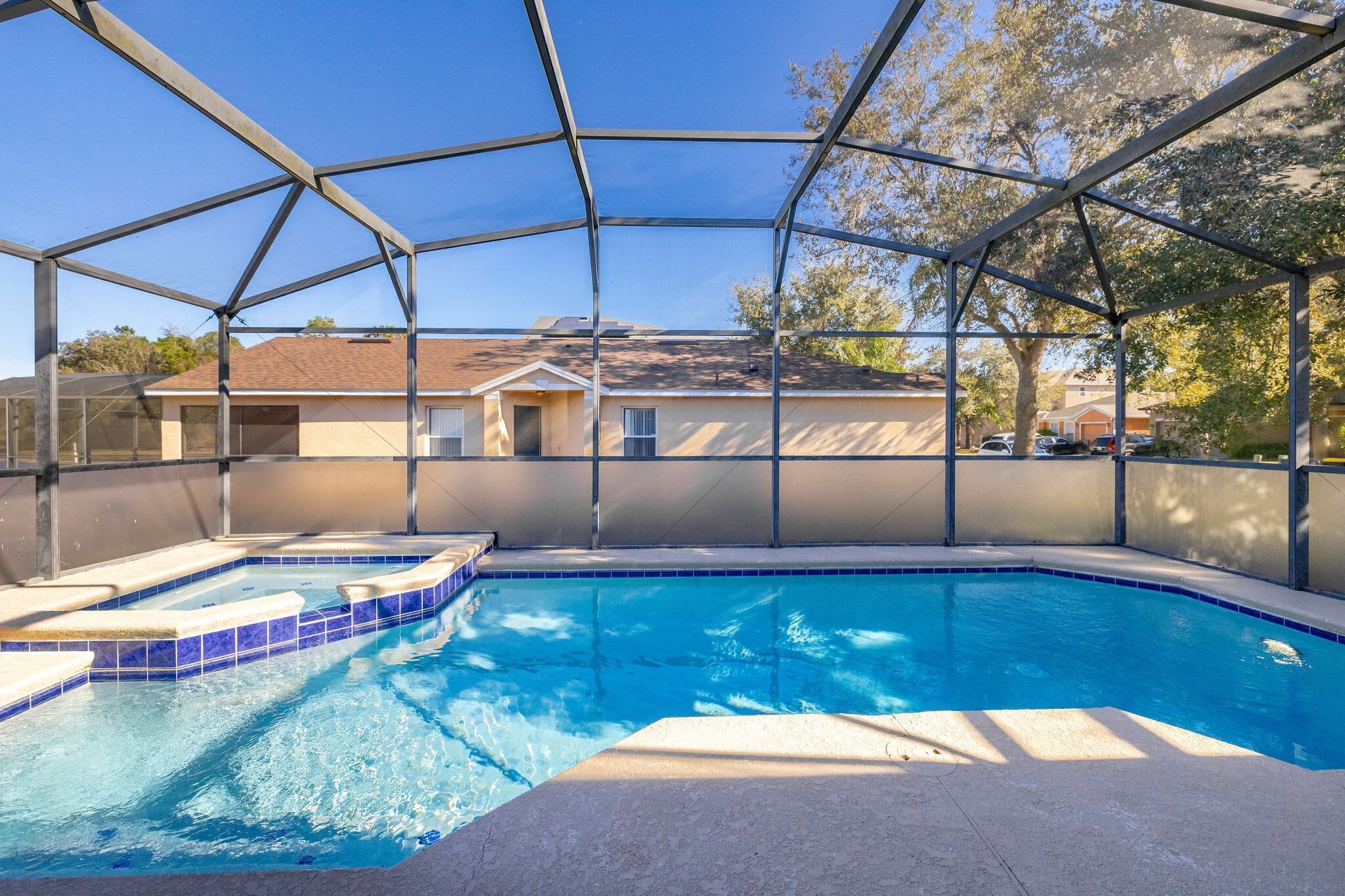 A swimming pool with a covered area, surrounded by a metal frame, and a house in the background.