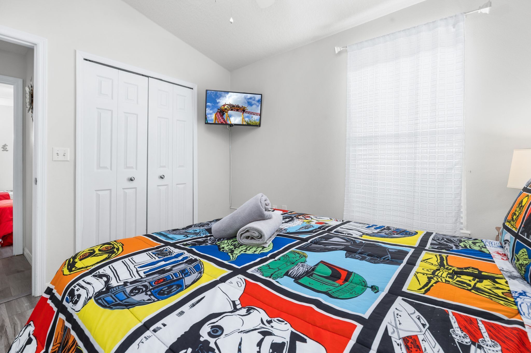 Una camera da letto con un letto, una televisione, una finestra con tende e una porta.