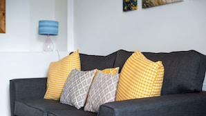 Un canapé gris avec des coussins à motifs jaune et gris.