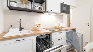 Moderni keittiö, jossa on astianpesukone, sisäänrakennettu uuni ja mikroaaltouuni.