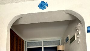 Een gebogen entree met een betegelde vloer, een houten deur en een witte kast.