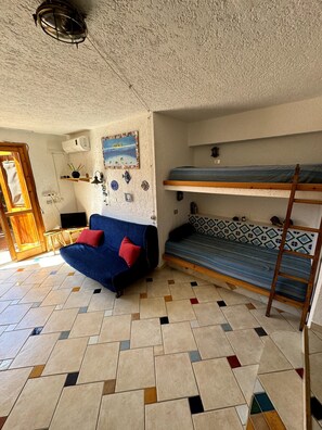 Une pièce comprenant un canapé, des lits superposés, une petite table et un mur décoré de différents objets.