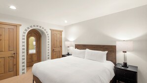 Ein Schlafzimmer mit einem großen Bett, zwei Nachttischen mit Lampen, einem Holzschrank und einem dekorativen Rundbogen.