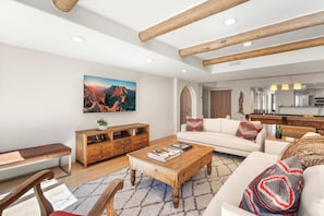 A spacious living room with a wooden coffee table, a sofa, a bench, and a large painting on the wall. - Sky House | Luxury Penthouse Vacation Rental on Main Street, Downtown Telluride (Telluride)