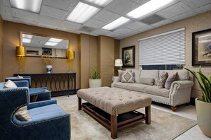 Una sala de estar con sofá, reposapiés y sillones, una mesa de centro, chimenea y un espejo grande.